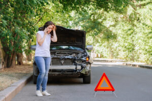 woman on cell phone after car has been involved in a hit and run accident